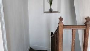 A staircase with wooden steps and a wooden handrail, leading to a landing with a white wall and a small window. - Town house located in LONGNES (Yvelines) (Longnes)