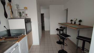 A modern kitchen with a built-in oven, a dishwasher, and a small dining area with a table and chairs.