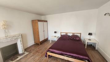 Un dormitorio con una cama de madera, dos mesitas de noche con lámparas, un armario de madera y una chimenea.
