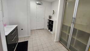 A modern bathroom with a white vanity, a glass shower enclosure, and a white door with a small shelf above it. - Town house located in LONGNES (Yvelines) (Longnes)