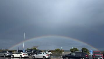 A parking lot with cars and a visible rainbow.