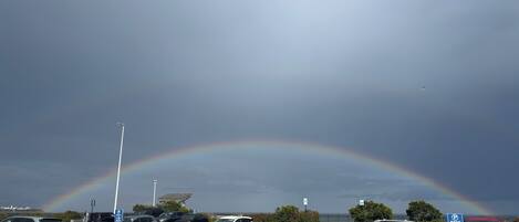 A parking lot with cars and a visible rainbow.