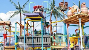 A colorful playground with various play structures, including a slide and climbing areas, surrounded by palm trees. - Mainsail Inn & Cottages (Hampton)