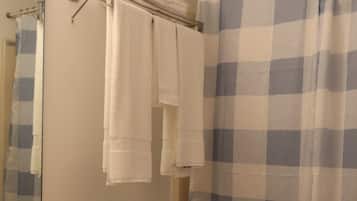 A bathroom with a sink, mirror, toilet, and a shower curtain.