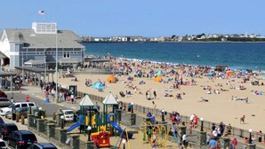 A beach with a playground and a building in the background. - Mainsail Inn & Cottages (Hampton)
