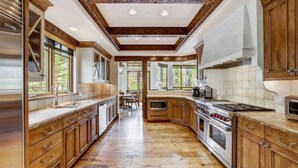 A spacious kitchen with wooden cabinets, a large stove, and a dining area visible through the windows. - 5 Bedroom Luxury Townhome in Lionshead Village (Vail)