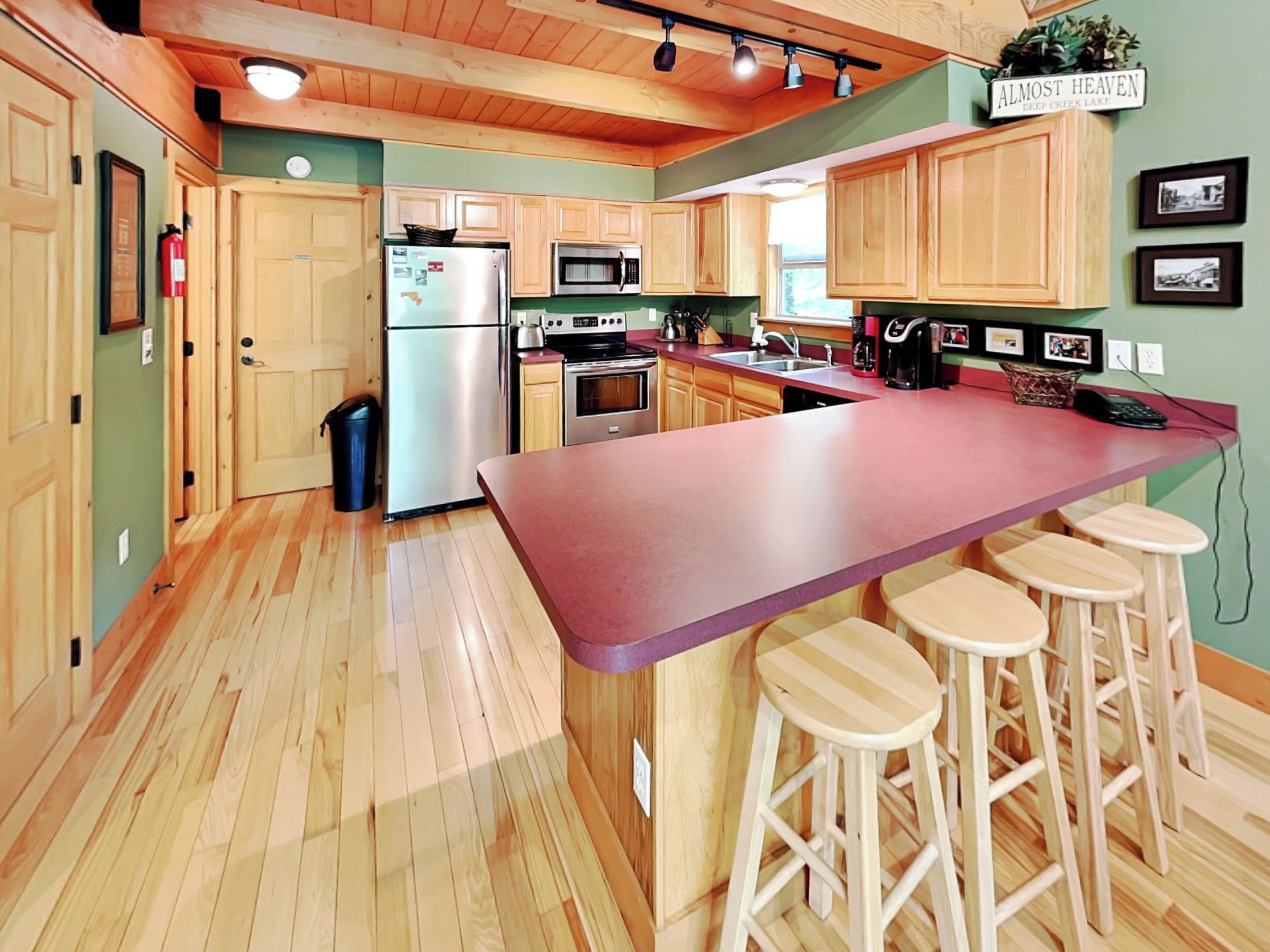 A kitchen with wooden cabinets, a stainless steel refrigerator, a microwave, and a large island with bar stools.