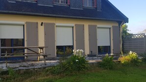 Ein Gebäude mit sechs Garagenzufahrten, einem Picknicktisch und einem Garten mit weißen Blumen.