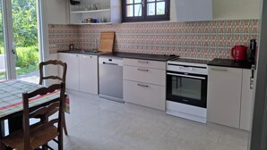 Eine Küche mit weißen Schränken, einem Geschirrspüler, einem Backofen und einem Fenster über der Spüle.