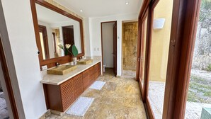 A modern bathroom with a large mirror, wooden vanity, and a view of the outdoor area. - Tropical Bungalow With Pool at cap Cana A8C (Punta Cana)