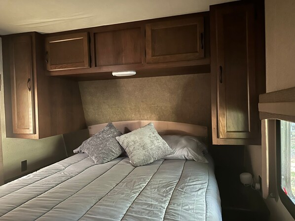 Ein Schlafzimmer mit einem Bett, Kissen und Holzschränken darüber.