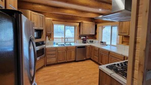 A kitchen with wooden cabinets, a stainless steel refrigerator, a microwave, a dishwasher, and a gas stove. - Wilderness Cabin In Colorado Mountains (Gunnison County)