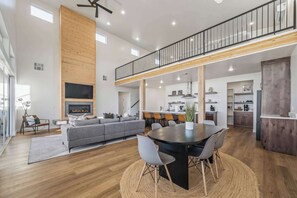 Uma sala de estar ampla com um sofá grande, uma mesa de jantar e uma cozinha ao fundo.