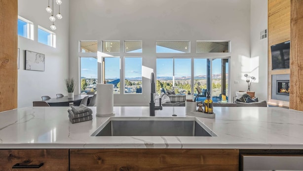 A modern kitchen with a large island, a dining area with a view, and a fireplace. - The Meadow at Natl Parks -Hot Tub- Sleeps 10-Family (Hatch)