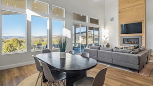 A spacious living area with a large dining table, grey sofa, and a fireplace. - The Meadow at Natl Parks -Hot Tub- Sleeps 10-Family (Hatch)
