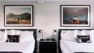 A hotel room with two beds, a nightstand with lamps, and two framed pictures on the wall.