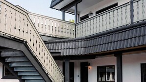 Un bâtiment moderne doté d’un espace extérieur abrité, d’un escalier et de deux chaises.