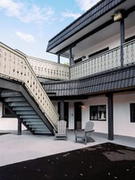 Un edificio moderno con un área exterior cubierta, una escalera y dos sillas.