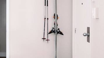 A room with a ski rack mounted on the wall and a pair of skis and ski boots on the floor.