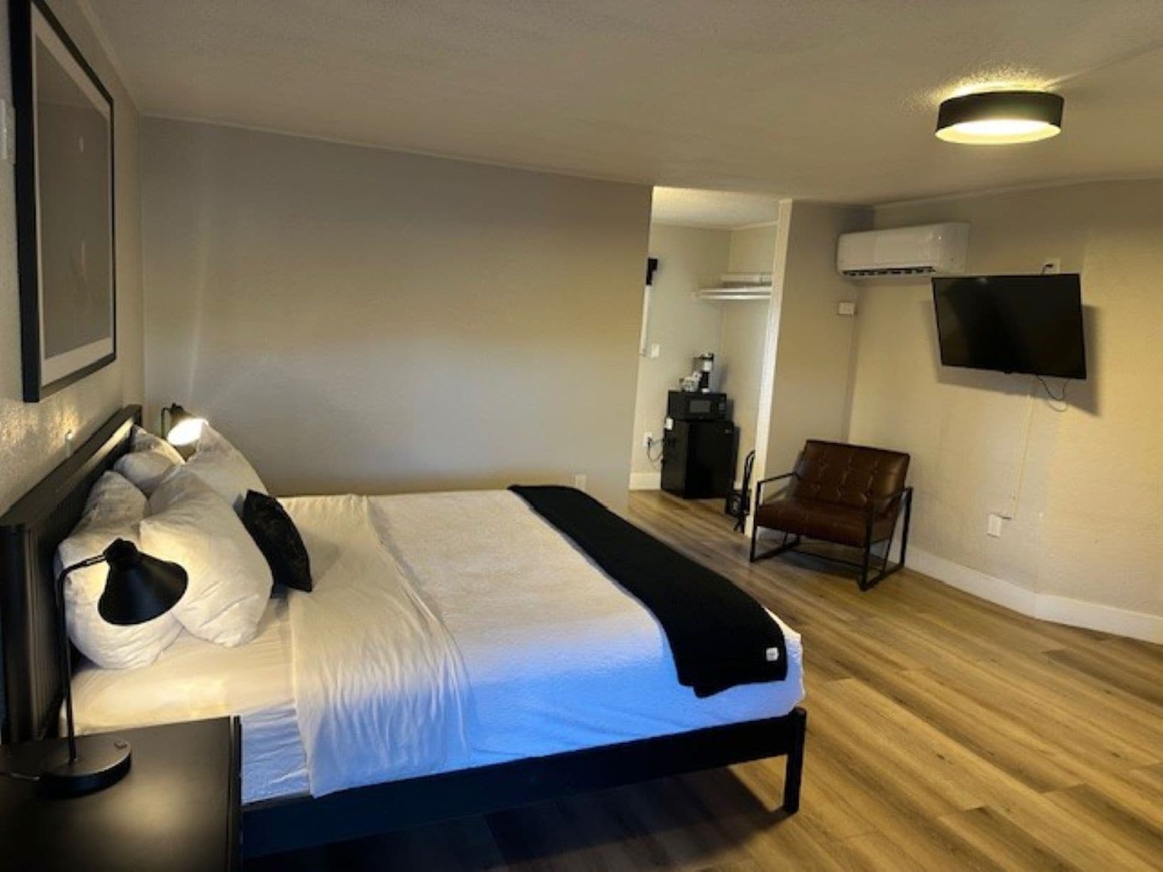Une chambre à coucher comprenant un lit, une chaise, un téléviseur et un appareil de climatisation.