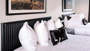Une chambre d’hôtel avec un grand lit, une tête de lit et un tableau représentant un paysage.