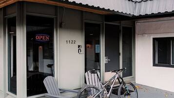 A building with a corrugated metal roof, a bicycle parked outside, and a chair near the entrance.