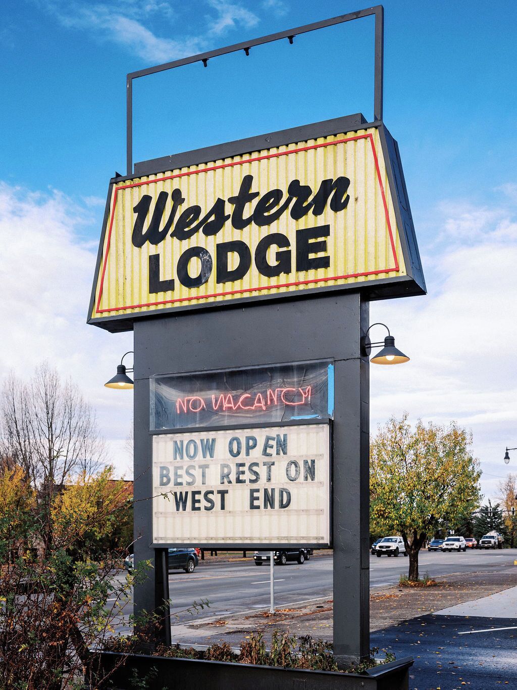 A Western Lodge sign with a neon marquee and a message stating "NO VACANCY" and "NOW OPEN BEST REST ON WEST END".