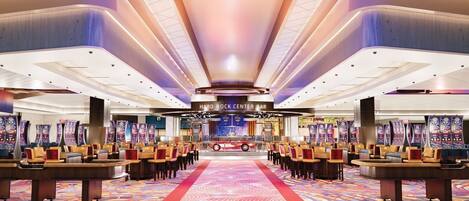A spacious lobby with a central bar area, multiple gaming machines, and rows of seating.