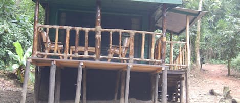 Una cabaña de madera con balcón, rodeada de árboles.