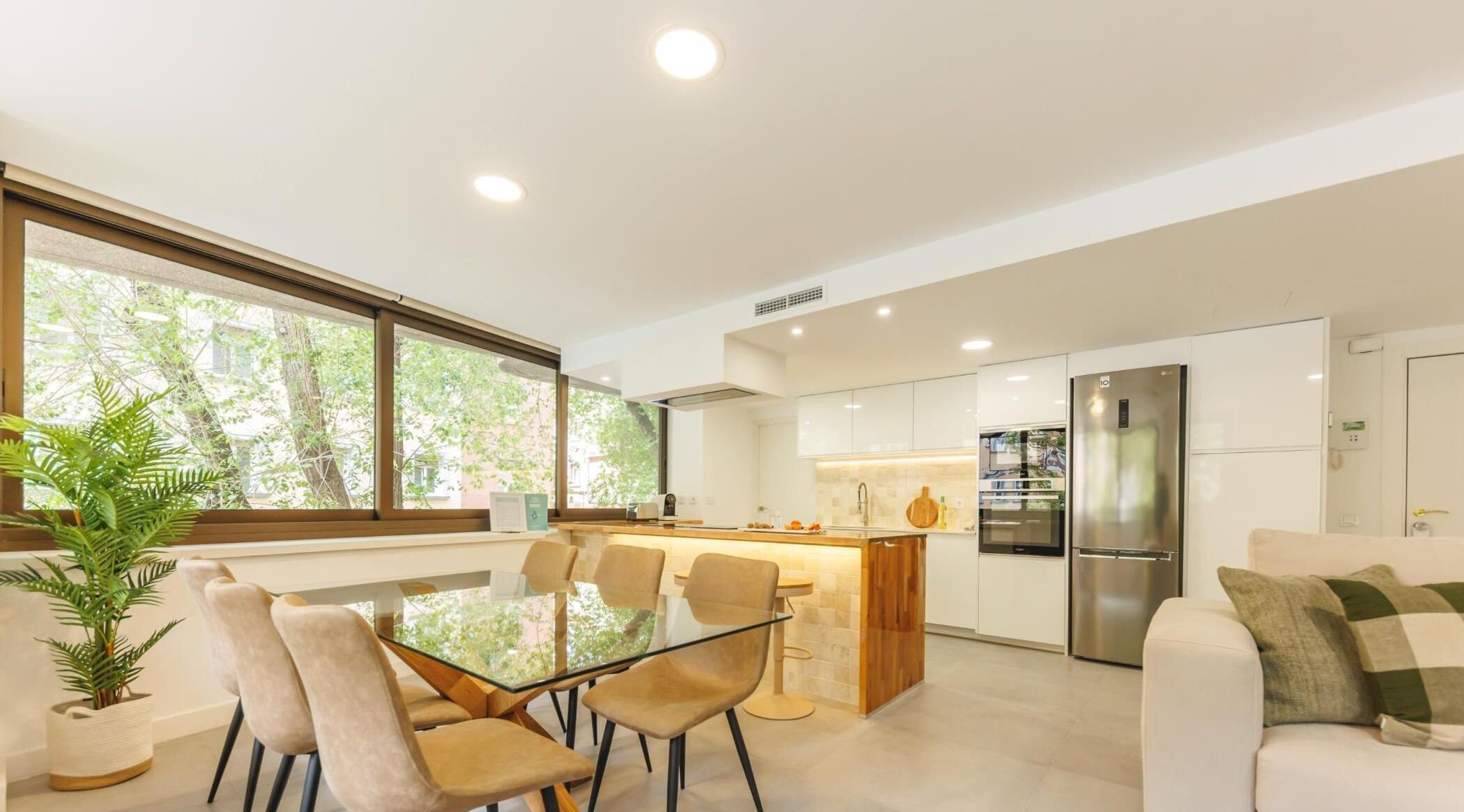 Une cuisine moderne dotée d’un îlot central, de meubles blancs et d’un réfrigérateur en acier inoxydable.