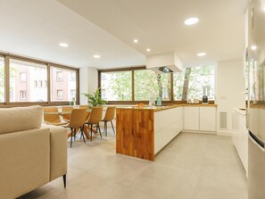 A modern kitchen with a wooden island, white cabinets, and large windows. - Bravissimo Turbau Entresol A, with 3 bedrooms (Girona)