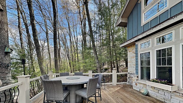 A wooden deck with a round table and chairs, surrounded by a white fence, overlooking a forested area. - Acorn Cottage by Taylor Made Deep Creek (Oakland)