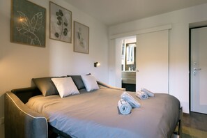 A modern hotel room with a large bed, a bedside table, and a bathroom visible through an open door. - Monolocale - Darsena (Milano)