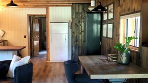 Un intérieur en bois comprenant un bar, un réfrigérateur et une table à manger avec des chaises.