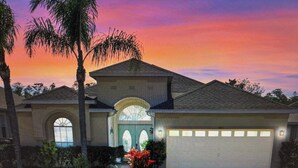 A single-story house with a garage, a front porch, and a well-maintained garden. - Luxury 4 bed villa private pool & spa, close to Disney Parks on Golf Community (Davenport)