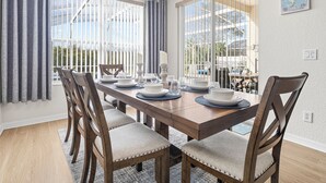 A dining area with a wooden table set for four, surrounded by upholstered chairs. - Luxury 4 bed villa private pool & spa, close to Disney Parks on Golf Community (Davenport)