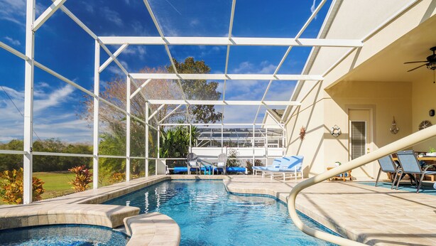 A swimming pool with a glass enclosure, lounge chairs, and a view of the outdoors. - Luxury 4 bed villa private pool & spa, close to Disney Parks on Golf Community (Davenport)