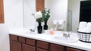 Un bagno con due lavandini, uno specchio e un porta asciugamani.