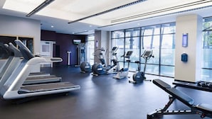 A modern gym with treadmills, elliptical machines, and free weights.