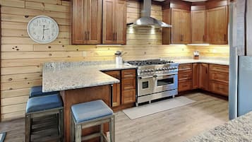 A kitchen with wooden cabinets, a stainless steel range hood, a double oven, and a granite countertop.