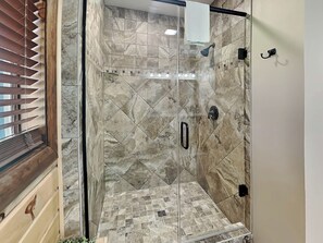 A glass-enclosed shower with a tiled floor and a handrail. - Falcon's Landing by Taylor Made Deep Creek (McHenry)