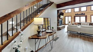 Un salon spacieux avec un escalier en bois, une cheminée et une grande fenêtre.