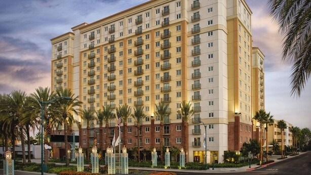 A multi-story hotel with a uniform facade, balconies, and a landscaped entrance area with palm trees. - WorldMark Anaheim - 2 Bedroom Presidential Accessible (Anaheim)