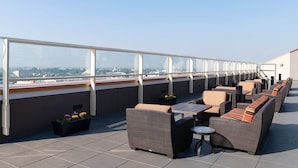 Une terrasse sur le toit, aménagée avec des meubles en osier, une petite table et des plantes en pot.