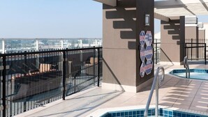 A rooftop pool area with a hot tub, a glass balustrade, and a view of the cityscape. - Anaheim | Theme Park Weekend Escape | Pool & Hot Tub (Anaheim)