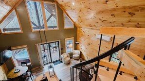 Interior acogedor de una cabaña con detalles de madera, una zona de comedor, un jacuzzi y una escalera.