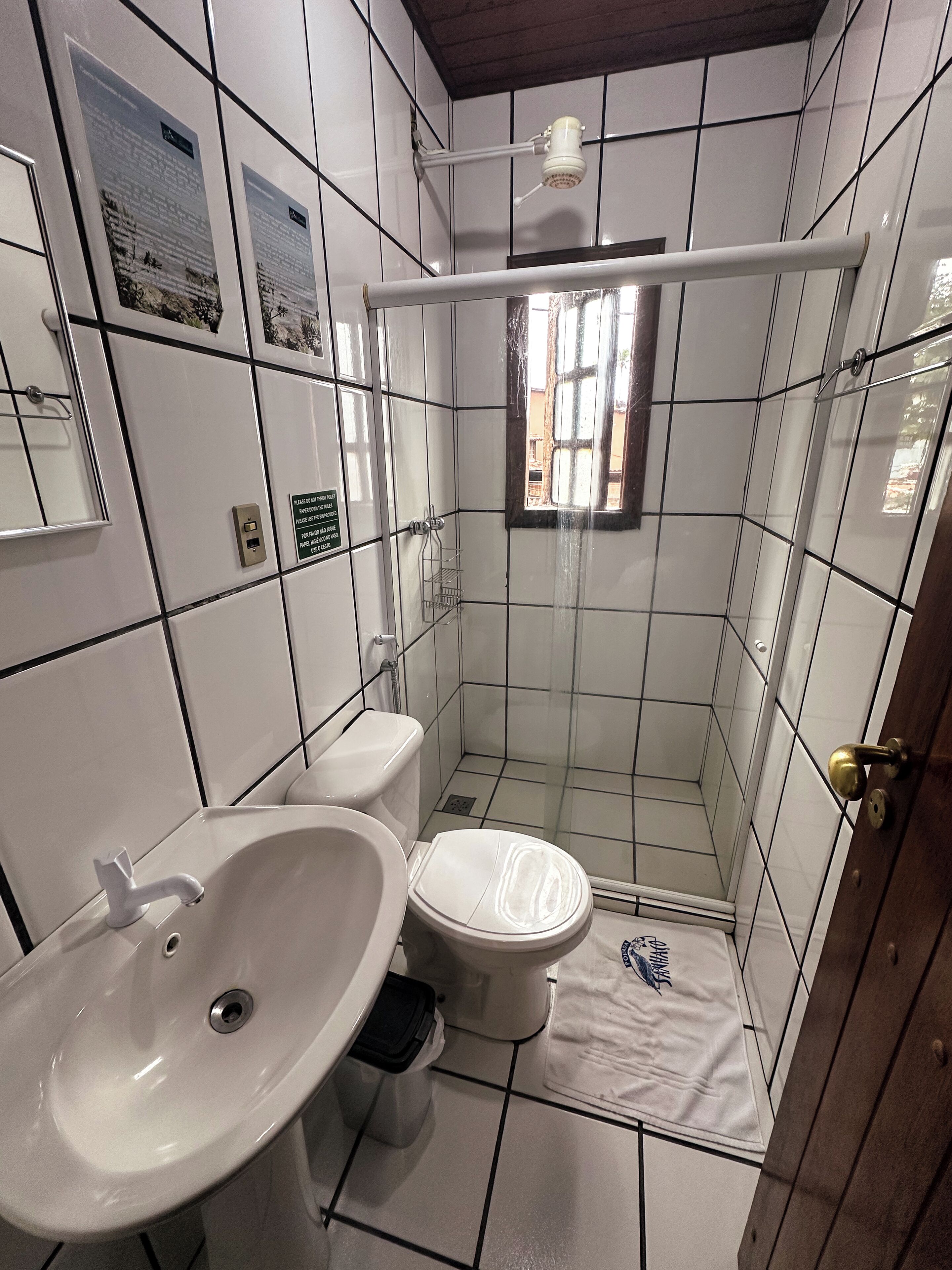 A bathroom with a toilet, sink, and shower. There are tiled walls and a window.