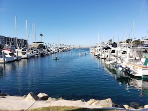 A marina with boats docked along the water's edge, a clear sky, and a calm sea. - Oceanside | Coastal Vibes | Pool & Hot Tub (Oceanside)