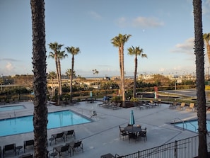A pool area with lounge chairs and palm trees. - Oceanside | Coastal Vibes | Pool & Hot Tub (Oceanside)