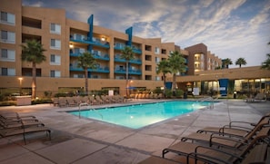A hotel with a swimming pool, lounge chairs, and palm trees. - Oceanside | Coastal Vibes | Pool & Hot Tub (Oceanside)